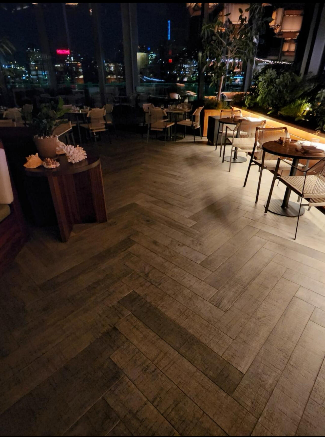Rooftop restaurant floor at night with herringbone tile and the city skyline behind